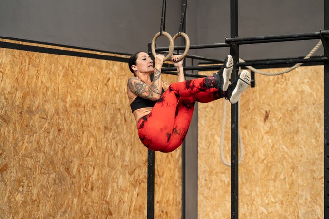 Woman training using olympic rings alone in a gym
