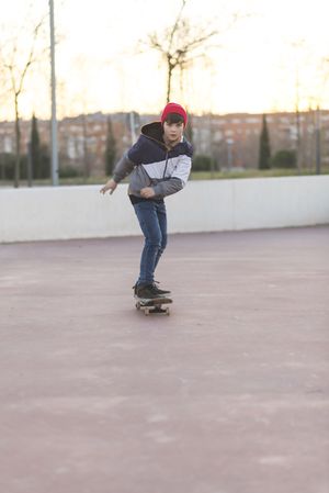 Front view of young man riding on skateboard in park