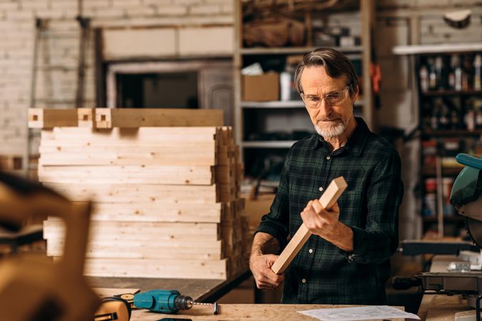 Mature male holding piece of wood in studio