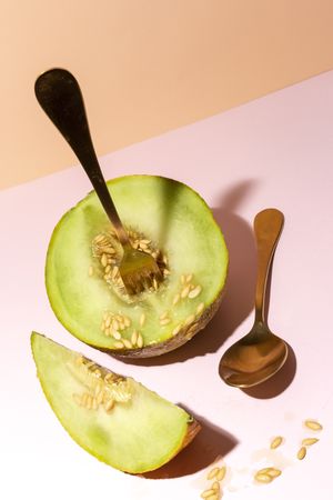 Sliced small melon on plate with spoon and fork