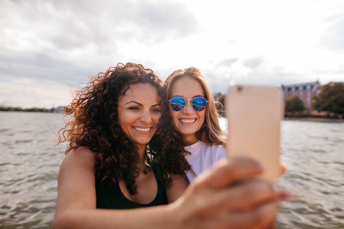 Female friends taking self portrait with smart phone on the water