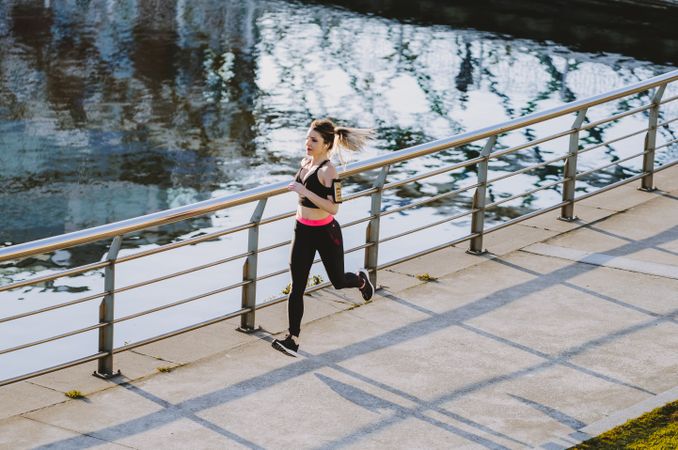 Woman running on embankment near water