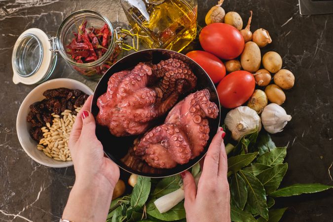 Faceless woman with raw octopus and various ingredients