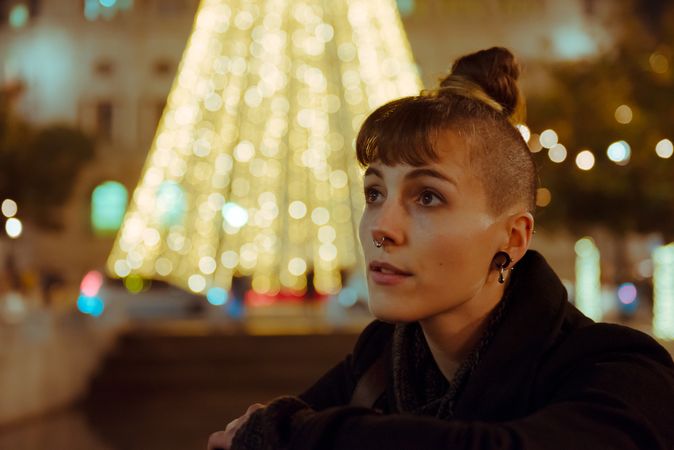 Woman in trendy outfit sitting near a Christmas tree