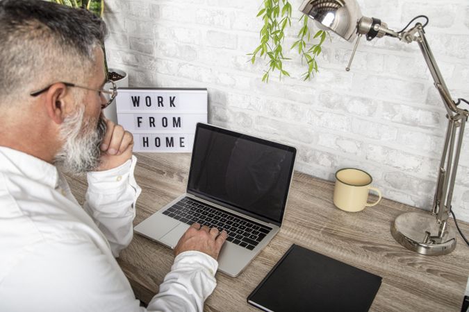 Rear view of a man working on his laptop in his home office