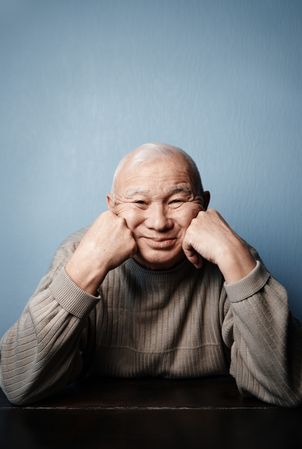 Smiling mature man sitting at the table and looking at camera