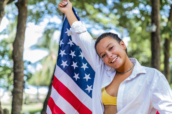 Content woman smiling wrapped in American flag walking along park