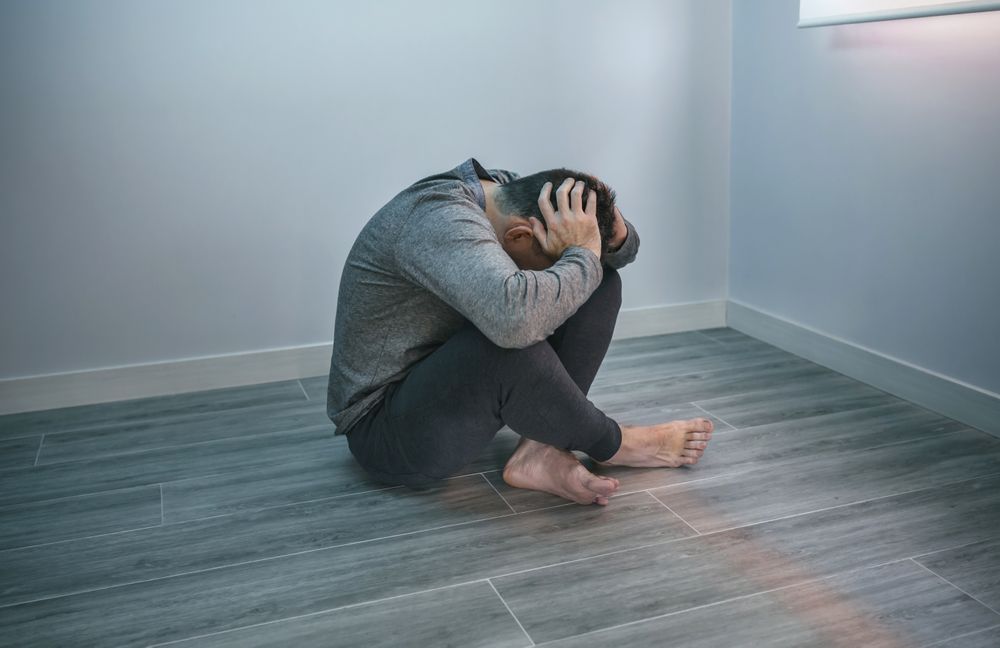 Unrecognizable man with problems sitting on the floor