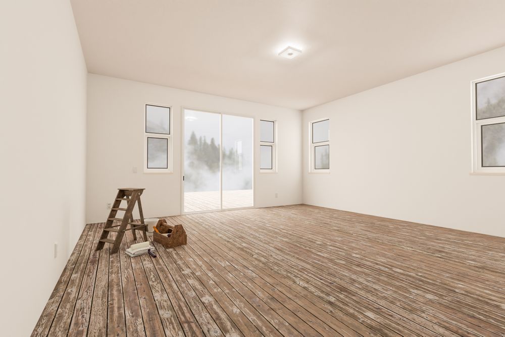 Ladder and Painting Equipment In Raw Unfinished Room of House with Blank Walls and Worn Wood Floors.