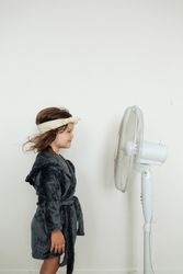 Little girl standing against fan at home