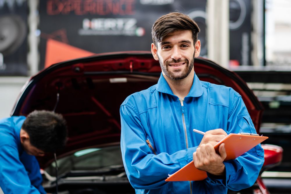 Male auto worker standing with clipboard in front of vehicle
