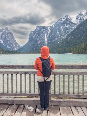 Anonymous traveler admiring mountains and lake from pier