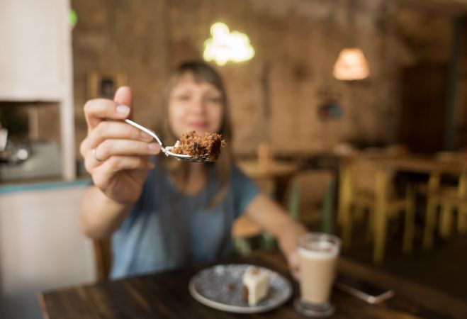 Woman holding spoon with slice of cake