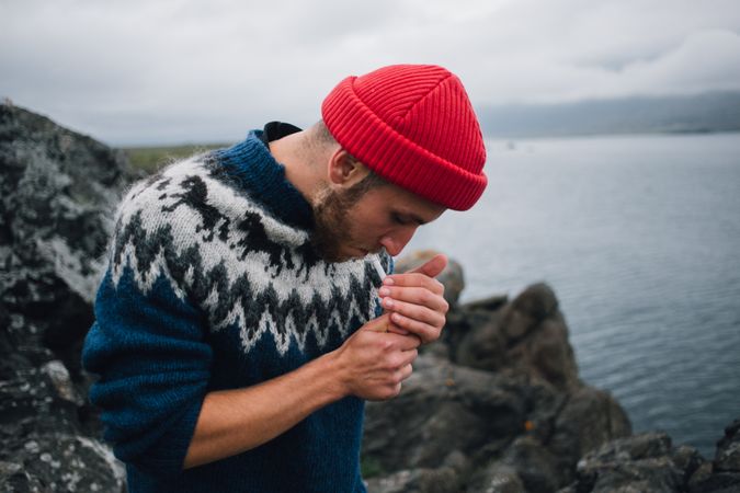 Man lighting cigarette on rocky coastal terrain