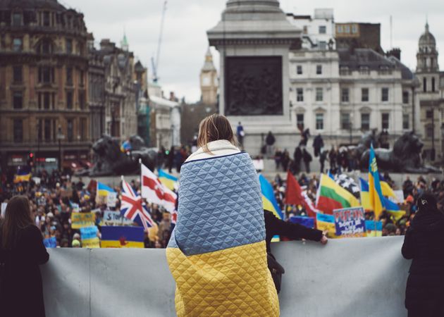 London, England, United Kingdom - March 5 2022: Woman at protest wrapped in Ukrainian flag blanket