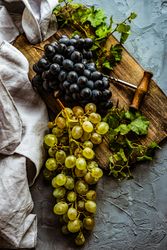 Top view of grapes on board with wine opener with kitchen towel