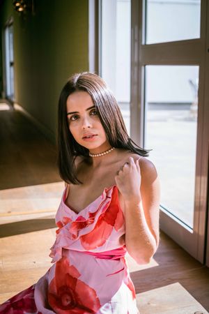 Stylish young woman in dress posing in room