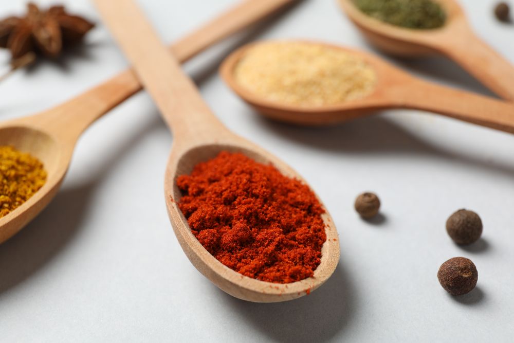 Close up of wooden spoons full of colorful earth tone spices
