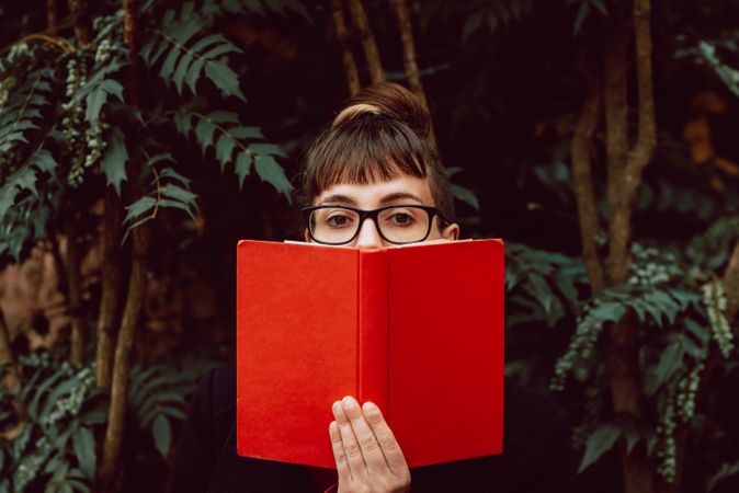 Young woman reading book on bench in park