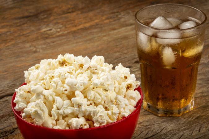 Bowl with salted popcorn and soda on the table.