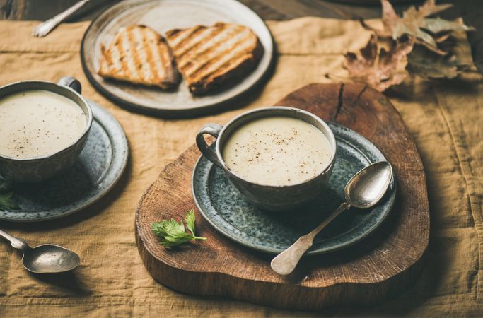Celery soup in cups with toast on wooden board