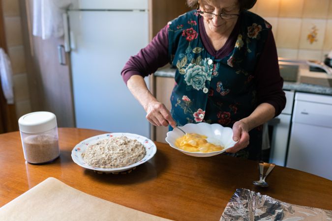 Mature woman beating eggs to coat the croquettes