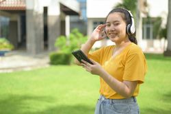 Asian woman wearing music headphones looking at camera
