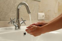 Woman washes her hands with soap in the sink