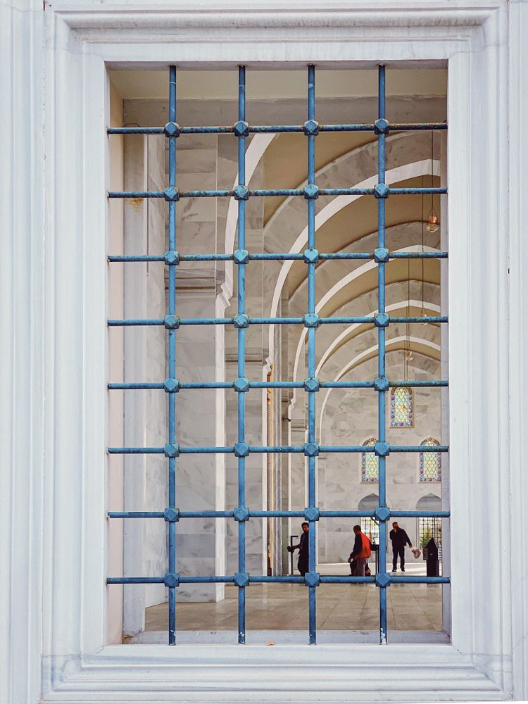 Window with metal bars looking into mosque