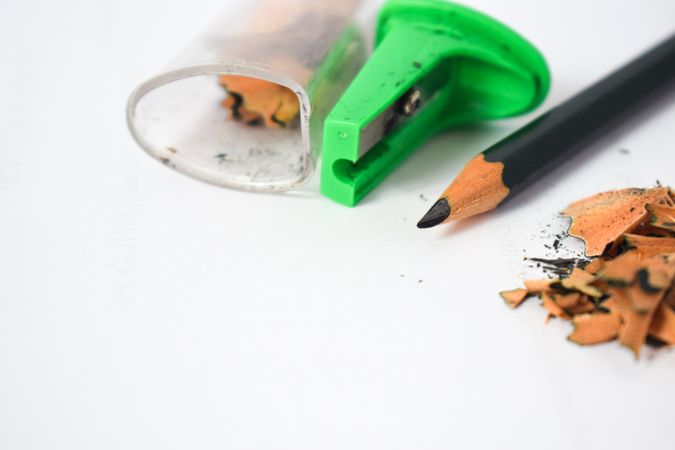 Pencil on table next to green sharpener and shavings with space for text
