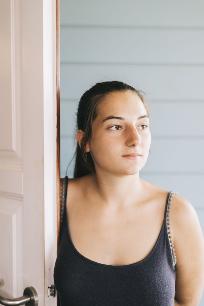 Portrait of a young woman entering door in summer dress