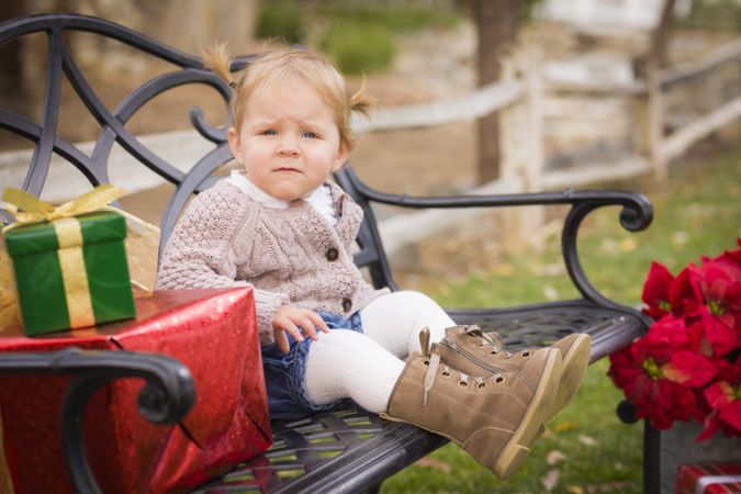 Young Toddler Child Sitting on Bench with Christmas Gifts Outside