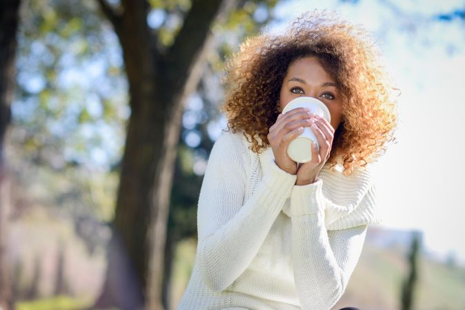 Black woman sipping coffee from to go drink outside