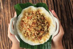 Hands holding lumpia dish served, top view