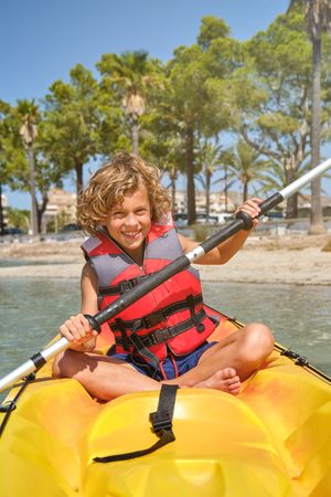 Smiling child on kayak rowing in sea during vacation