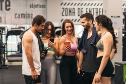 friends talking and using mobiles in a gym
