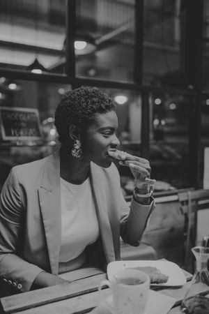 Black woman eating a sandwich at table in cafe