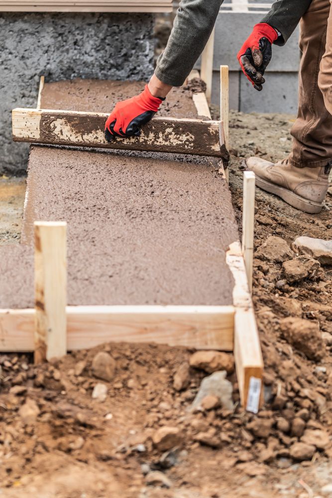 Construction Worker Leveling Wet Cement Into Wood Framing