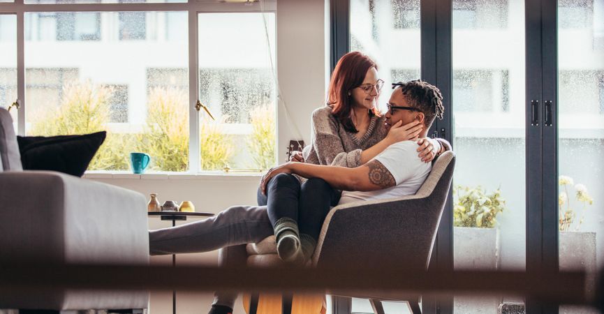 Romantic couple relaxing on armchair in living room