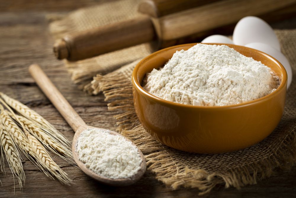 Bowl with wheat flour on the table.