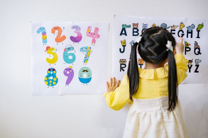Back view of girl learning ABC and numbers on light board