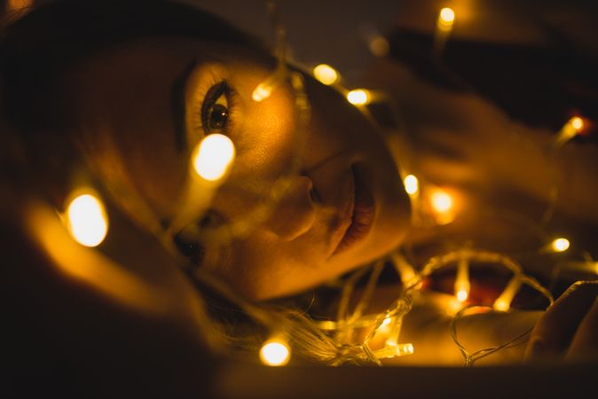 Woman lying surrounded by light garland