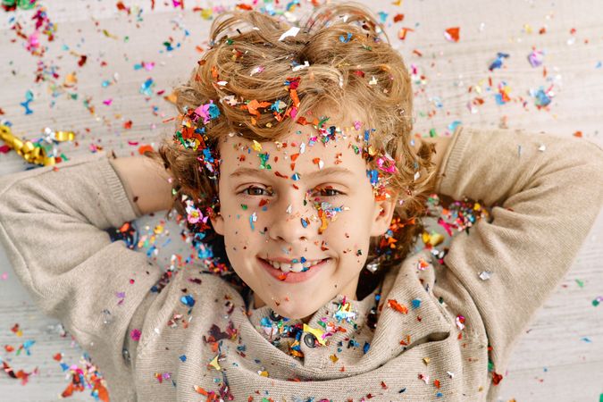Positive kid strewn with confetti