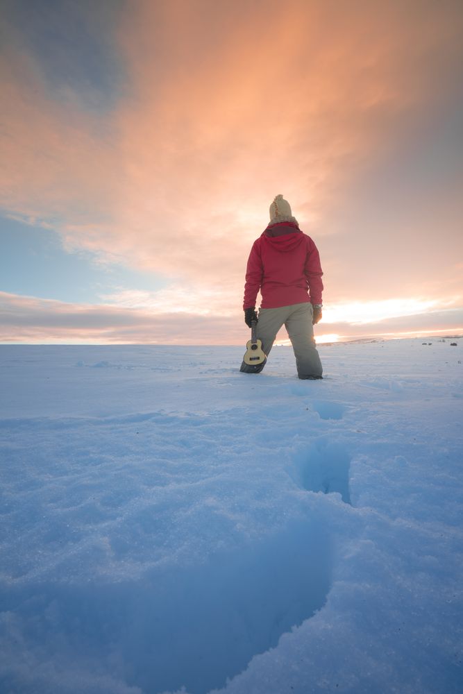 Traveler standing on snow against sunset sky