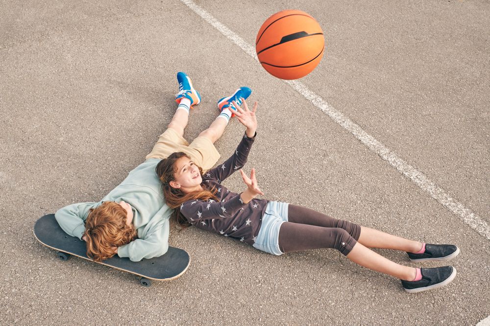 Cheerful teenage girl and boy lying on sports ground