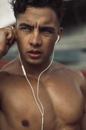 Close up of athletic male putting on earphones to listen to music