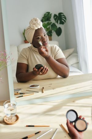 Black woman applying makeup at home