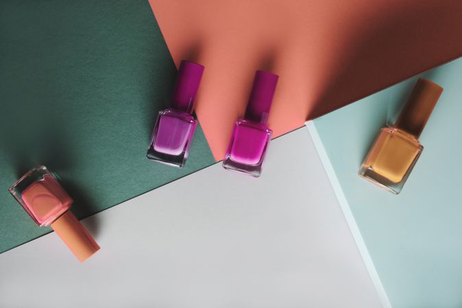 Multi-colored nail polish on pastel colors geometric pattern background
