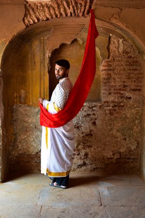 Man in traditional outfit  standing beside wall