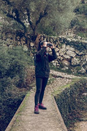 Female hiker using binoculars during trekking in forest